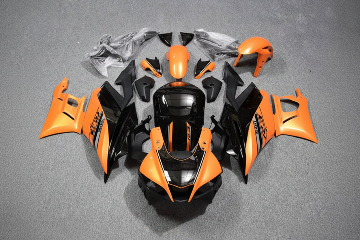 Motorcycle bodywork pieces in orange and black on a gray surface