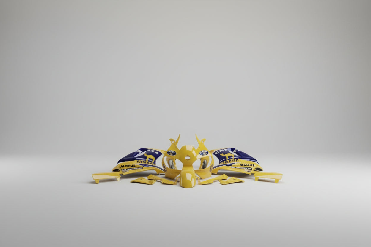 Yellow motorcycle body parts with branding on a white floor
