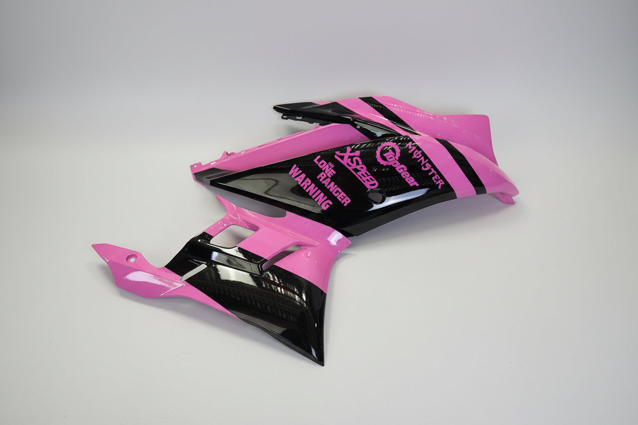 Pink and black motorcycle bodywork with branding on a white background