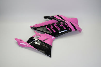 Pink and black motorcycle bodywork with branding on a white background