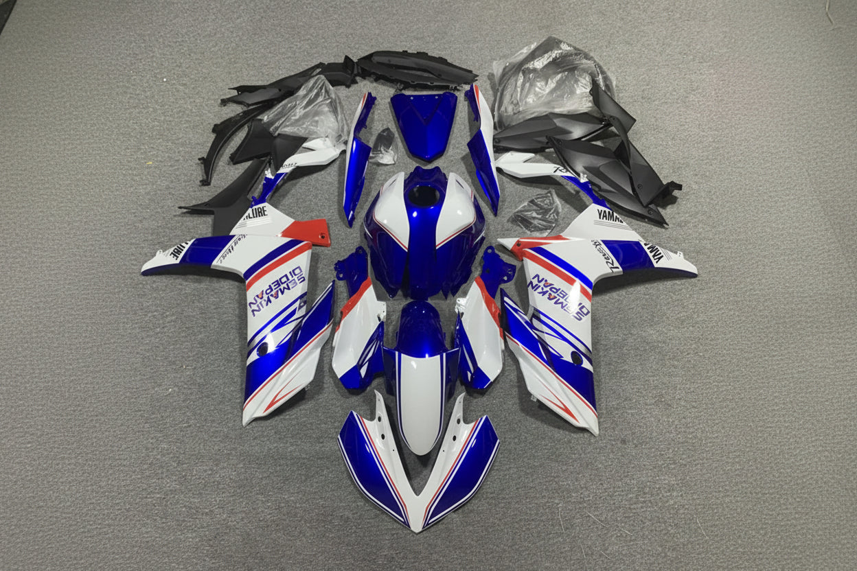 Motorcycle bodywork pieces in blue, white, and red on a gray surface